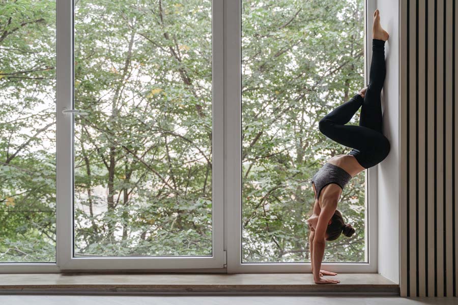 femme qui fait du yoga devant une fenêtre pvc blanc, dans un décor scandinave
